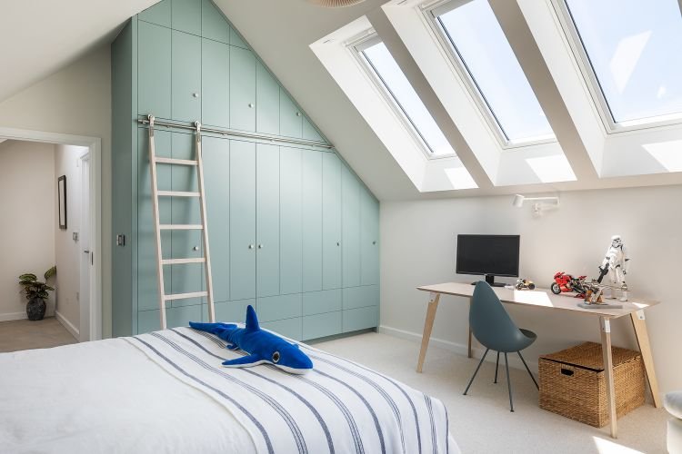 A kid's bedroom with a desk with computer display, Star Wars trooper and motorbike models. a ladder leans against page sage wardrobe.