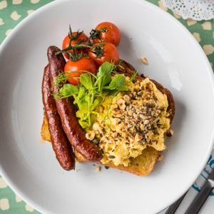 A plate sausage, eggs and tomatoes photographed from above.